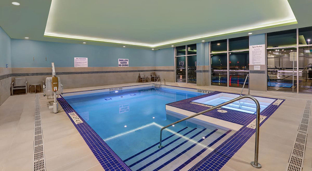 Indoor leisure pool with an accessibility lift and a spa with underwater lights at the Holiday Inn Express in Collingwood, Ontario